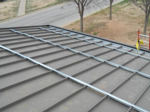 Notched sub-purlins were installed perpendicular to standing seams of the existing metal roof to provide the frame on which to attach the new metal roof.