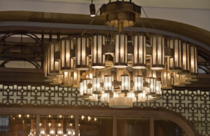 The custom-made chandeliers elegantly follow an octagonal shape with metal foundations formed in two layers, which embrace flat glass components in white and golden tones.