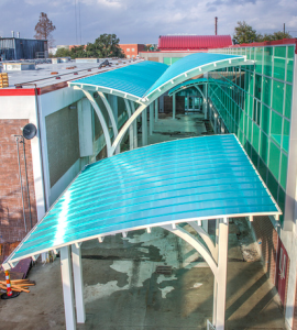Translucent green canopies manufactured by CPI Daylighting provide shelter over a courtyard joining the original Chalmette High School with its new addition.