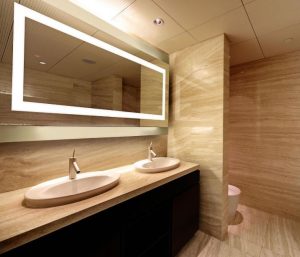 The rectangular wall-mounted mirrors feature lights that are unseen behind white translucent glass borders.